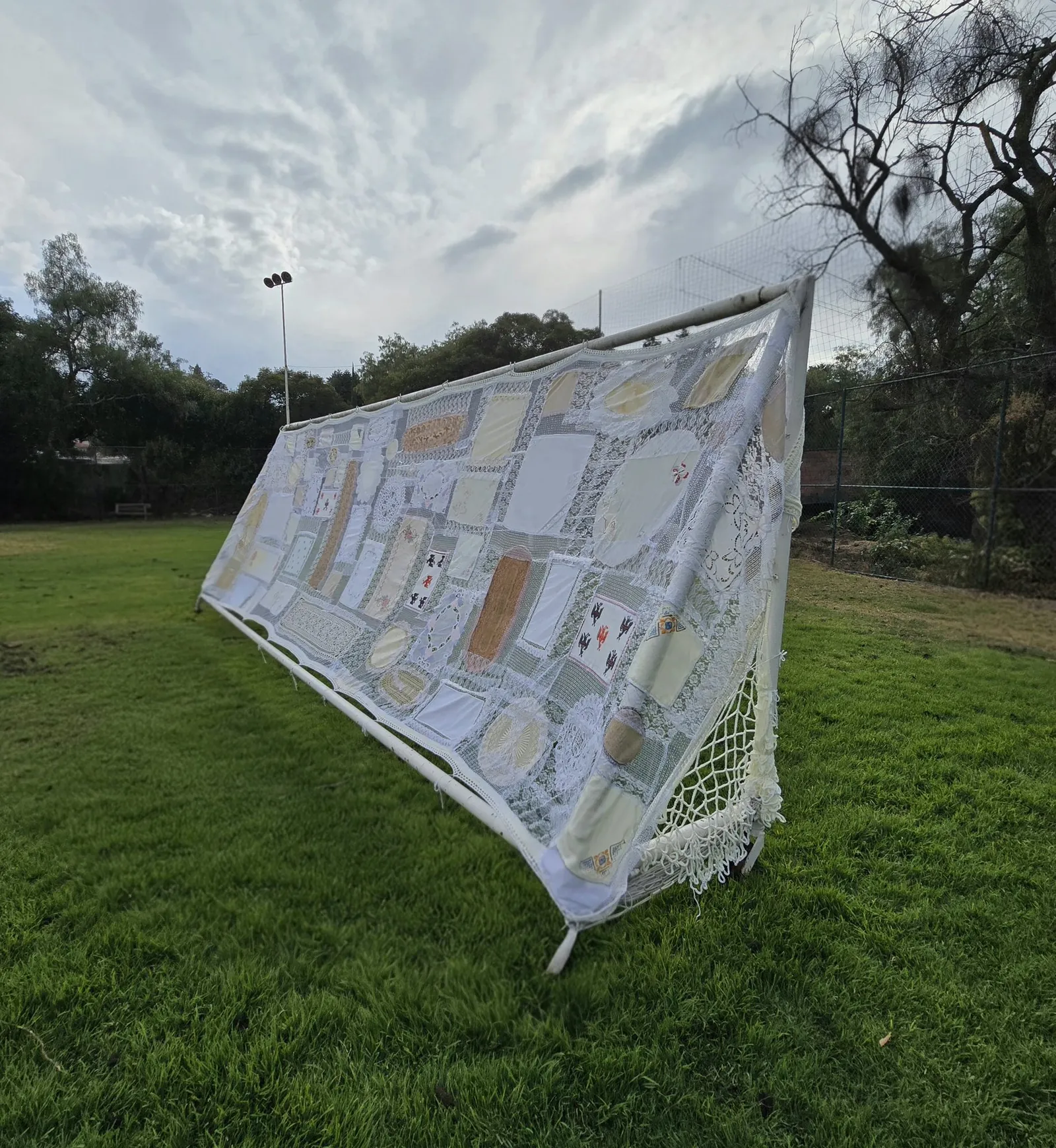 Umbral: la portería con textiles domésticos tensados, vista en ángulo con el cielo nublado